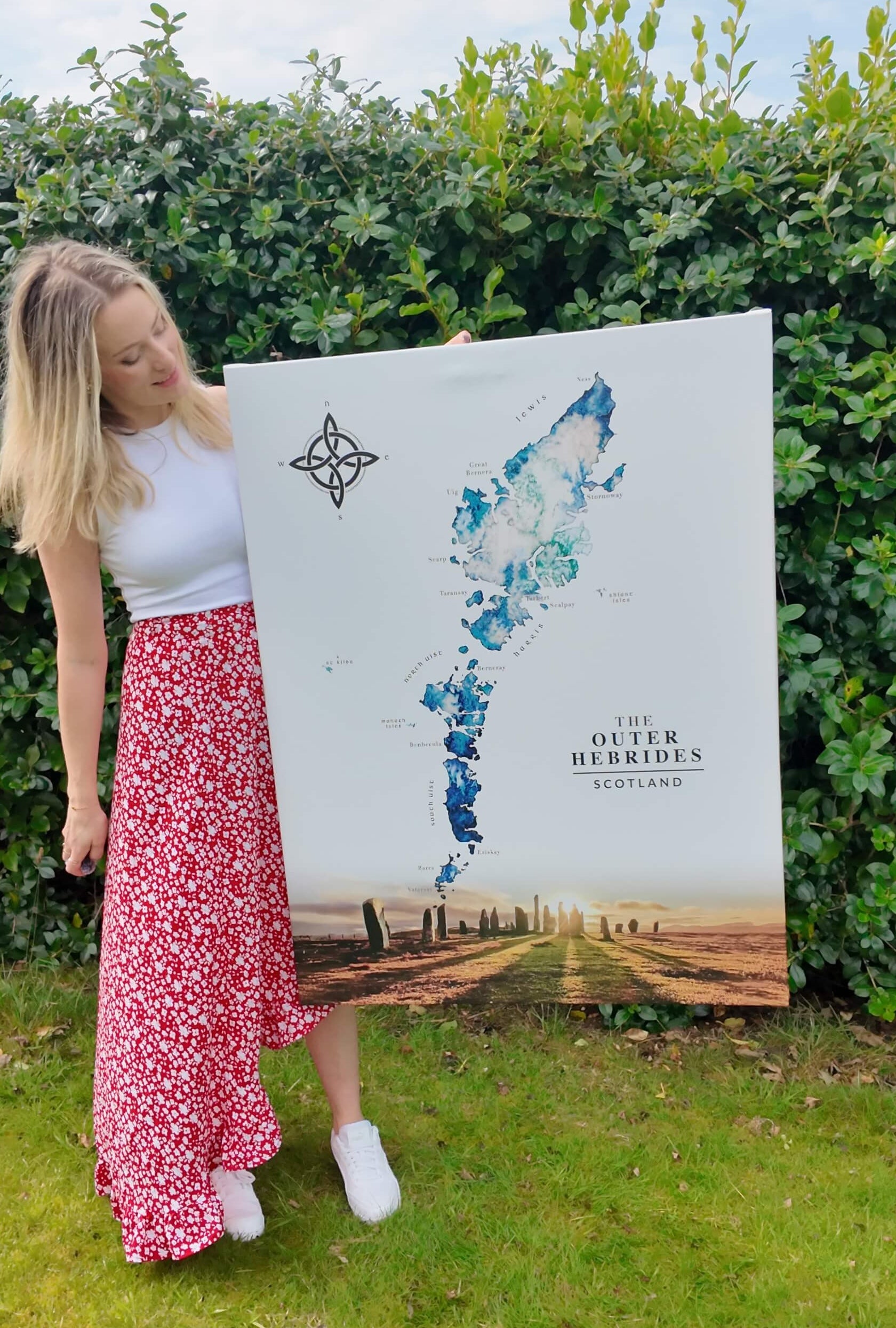 Scottish artist Eilidh Jamieson holding a large watercolour map of the Outer Hebrides Scotland, with the callanish stones at the bottom.