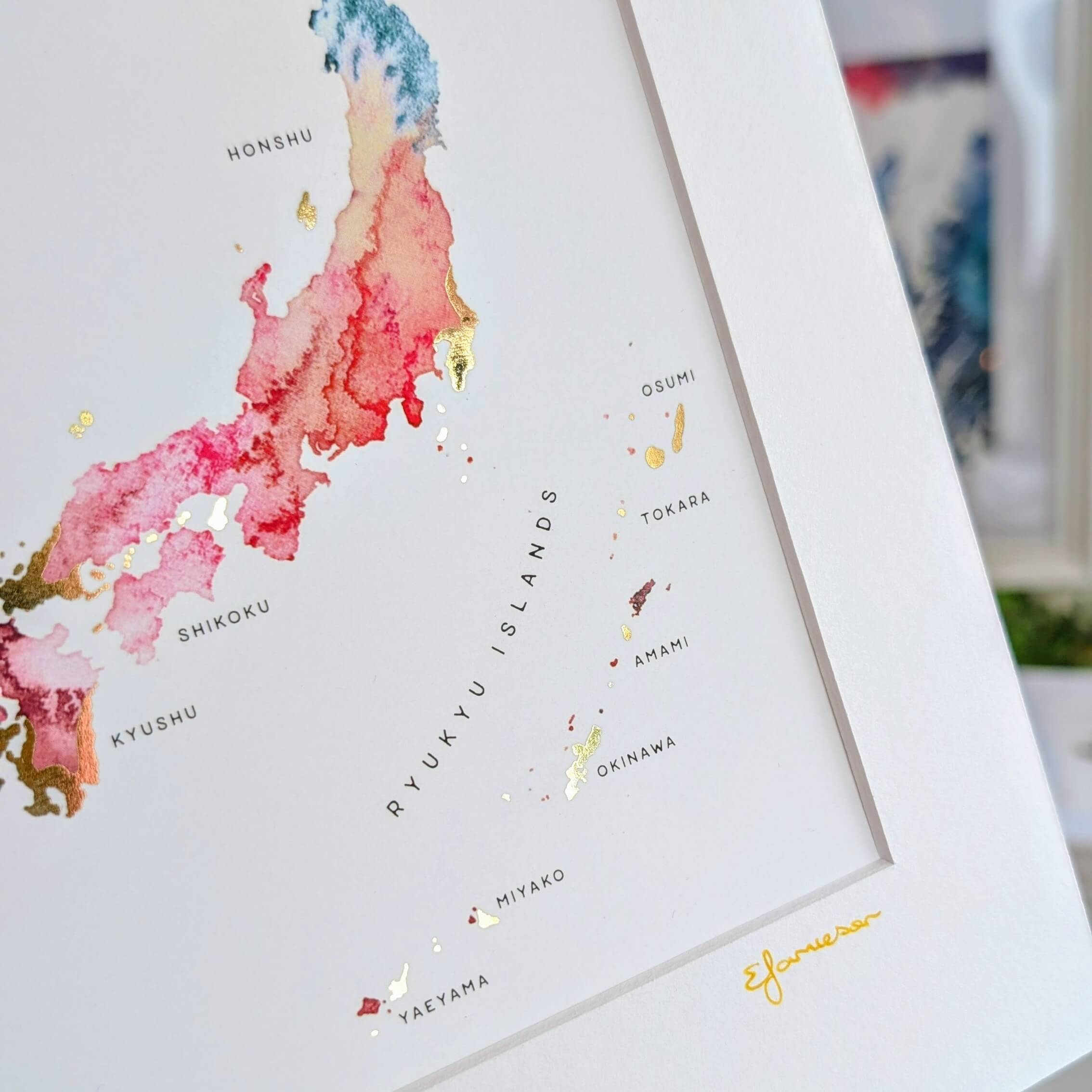Top-down perspective of a hand holding a Japanese islands watercolor print, capturing the depth of the mat board and detail in regions like Kyushu and Hokkaido.