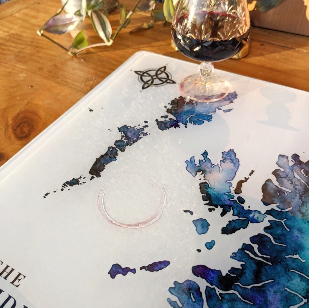 Wine glass on a decorative worktop saver with a watercolour map of the hebrides design